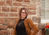 Photo of Author Rachel Sullivan. Canadian Endometriosis Advocate. Wearing yellow blazer in front of old stone house. 